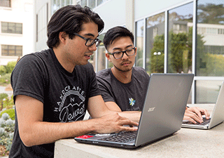 Data science students work together on a laptop